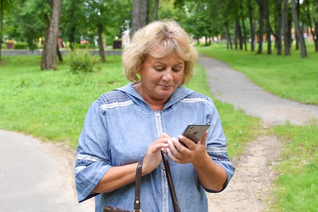 dorosła kobieta w parku rozmawia przez telefon kobieta w wieku komunikuje się online