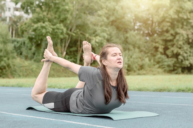 Dorosła kobieta wykonuje asany jogi na świeżym powietrzu