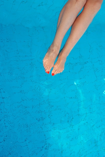 dorosłe białe nogi kaukaskiej europejskiej kobiety z pomarańczowym pedicure w basenie