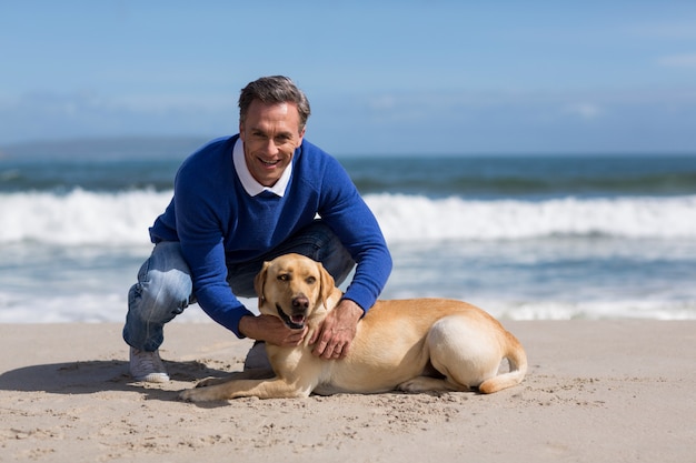 Dorośleć mężczyzna z jego psem na plaży