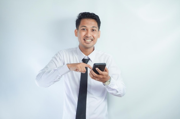 Zdjęcie dorosły azjat wskazujący na telefon komórkowy, który trzyma z wyrazem wow