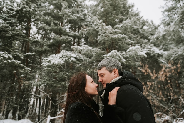 Dorosły mężczyzna i kobieta na tle zaśnieżonego lasu sosnowego zimą