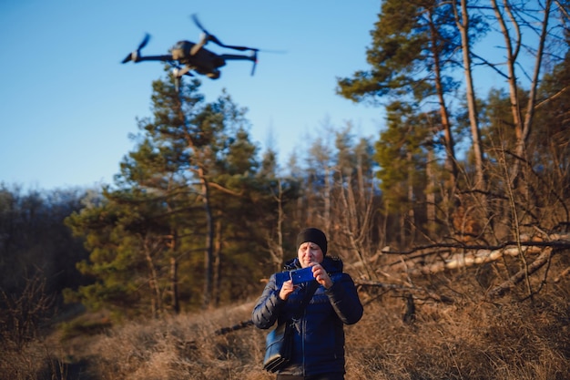 Dorosły mężczyzna przygotowujący się do zrobienia zdjęcia lub nagrania krajobrazu przyrody Mężczyzna fotograf trzymający smartfona i sterujący dronem