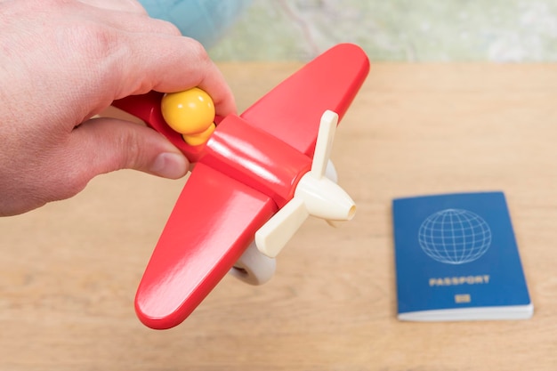 dorosły mężczyzna ręka grająca zabawka czerwony samolot na tle stołu z paszportem