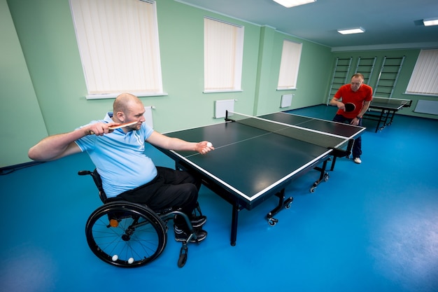 Dorosły Niepełnosprawny Mężczyzna Na Wózku Inwalidzkim Grać W Tenisa Stołowego Ze Swoim Trenerem