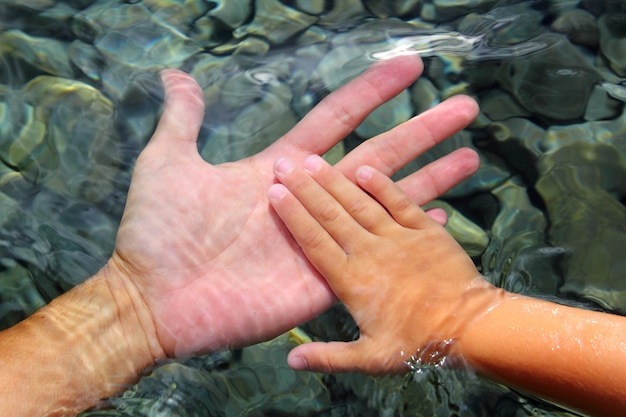 Dorosłych i dzieci ręce trzymając pod wodą