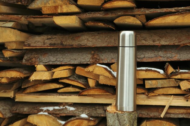 Zdjęcie dorywczo stalowy termos stojący na zewnątrz w pobliżu drewna opałowego