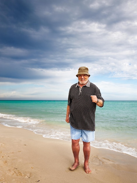 Dorywczo starszy mężczyzna robi ćwiczenia na plaży