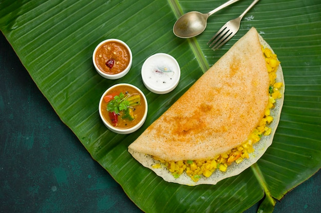 Dosa Masala dosafamous południowoindyjskie śniadanie, które jest wykonane w kasta żelaznej patelni w tradycyjny sposób i ułożone na świeżym liściu bananowca z ciemnozielonym tłem na białym tle