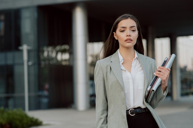 Dość eleganckie kobiety pozostawiają pracę po południu w nowoczesnym szklanym budynku w tle