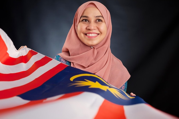 Dość młoda azjatycka muzułmanka posiada flagę Malezji piękną w akcji Islamska koncepcja modnego stroju