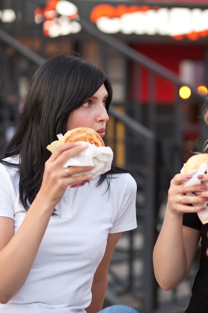 Dość Młoda Brunetka Kobieta Jedzenie Hamburgerów Odkryty Na Ulicy.