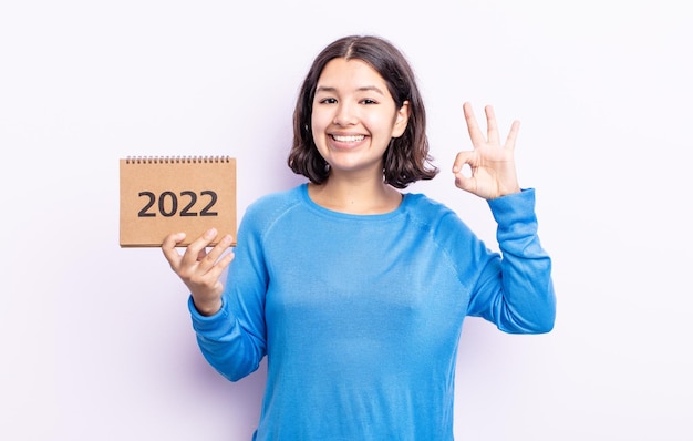 Dość młoda kobieta czuje się szczęśliwa, pokazując aprobatę w porządku gestem. koncepcja kalendarza 2022