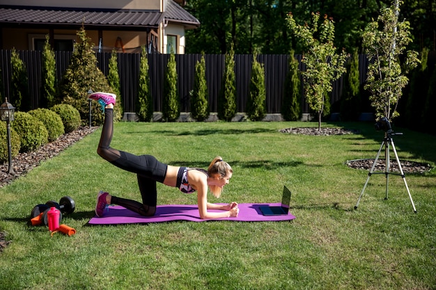 Dość sportowy trener fitness kobieta korzysta z laptopa podczas szkolenia wideo online