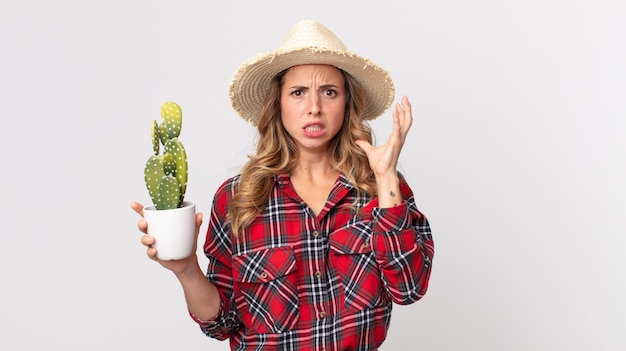 Zdjęcie dość szczupła kobieta krzyczy z rękami w powietrzu, trzymając kaktusa. koncepcja rolnika