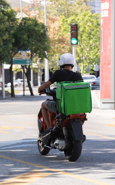 Dostawa jedzenia Kierowca skutera z zielonym plecakiem za plecami jest w drodze po jedzenie Kurier na skuterze dostarczający jedzenie Szybka wysyłka towarów do klientów