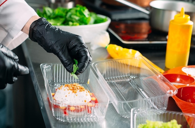 Dostawa jedzenia w restauracji. Szef kuchni przygotowuje posiłki w restauracji i pakuje je w naczynia jednorazowe.