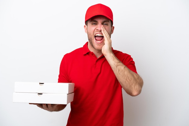 Dostawa pizzy kaukaski mężczyzna w mundurze roboczym podnoszący pudełka po pizzy na białym tle krzyczy z szeroko otwartymi ustami