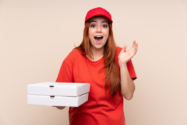 Dostawy pizzy nastolatka kobieta trzyma pizzę z niespodzianka wyrazem twarzy