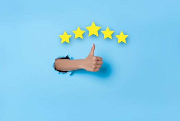 Zdjęcie doświadczenie klienta kobieta ręka kciuk w górę głosowania na pięć gwiazdek doskonała ocena na niebieskim tle. koncepcja przeglądu i opinii.