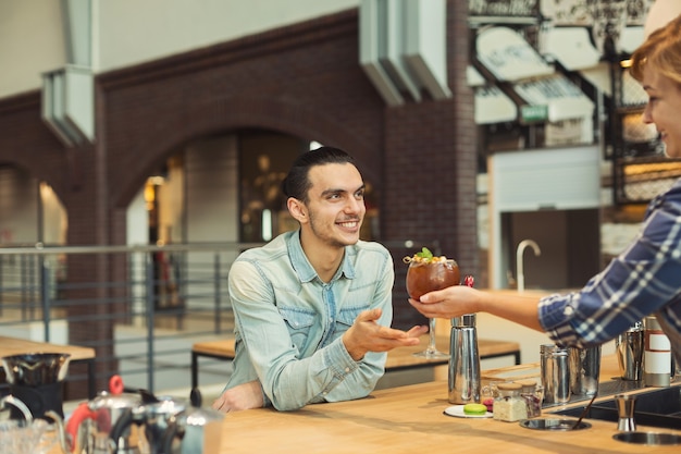 Doświadczony Barista W Mundurze Podający Filiżankę Kawy Mężczyźnie. Mały Biznes, Koncepcja Ludzi I Usług, Kopia Przestrzeń