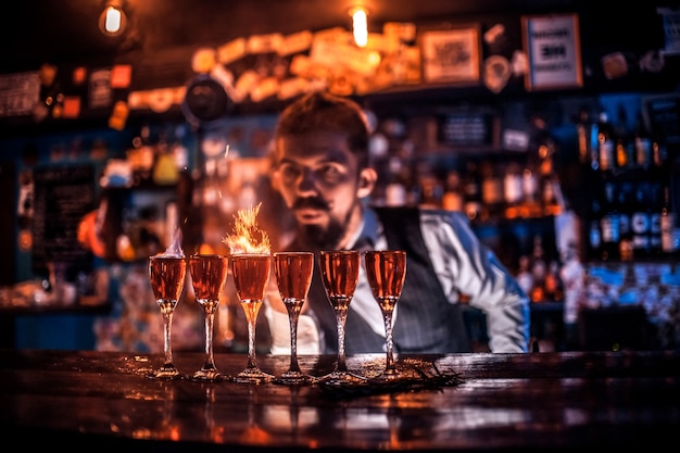 Doświadczony barman wlewający świeży napój alkoholowy do szklanek w barze