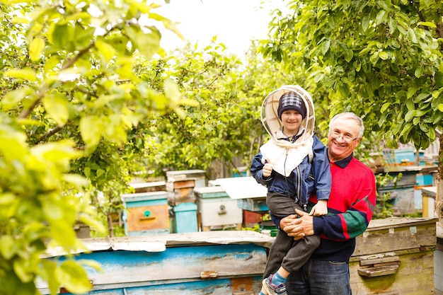 Doświadczony dziadek pszczelarz uczy swojego wnuka opieki nad pszczołami. Pszczelarstwo. Pojęcie transferu doświadczenia