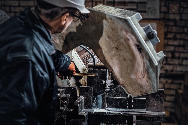 Doświadczony pracownik pracuje w fabryce metali przy użyciu specjalnej obrabiarki.