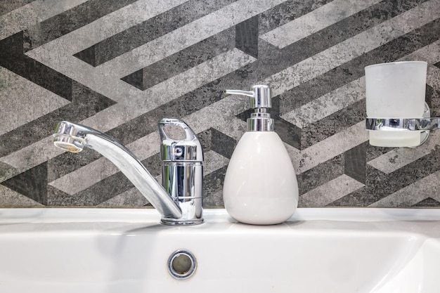 Dozowniki mydła i szamponu w pobliżu umywalki Ceramic Water z kranem w drogiej łazience lub kuchni na poddaszu