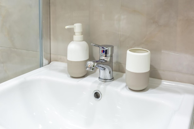 Dozowniki mydła i szamponu w pobliżu umywalki Ceramic Water z kranem w drogiej łazience na poddaszu