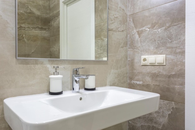 Dozowniki mydła i szamponu w pobliżu umywalki Ceramic Water z kranem w drogiej łazience na poddaszu