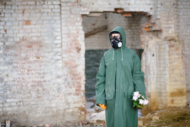 Zdjęcie dozymetrysta inspektor promieniowania w odzieży ochronnej i masce przeciwgazowej bada strefę zagrożenia zbliżenie kwiat katastrofa ekologiczna