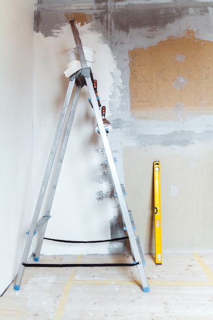Drabina z narzędziami do malowania w pokoju w domu lub mieszkaniu. Przygotowanie do szpachlowania na ścianie lub malowania. Koncepcja naprawy lub renowacji domu.