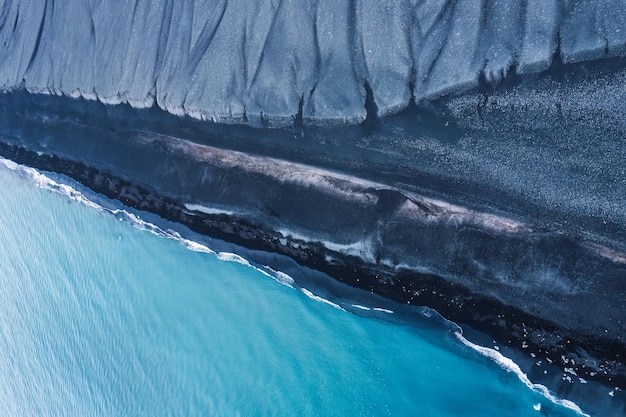 Zdjęcie dramatyczne niebieskie morze z falą erozji na czarnej piaszczystej plaży