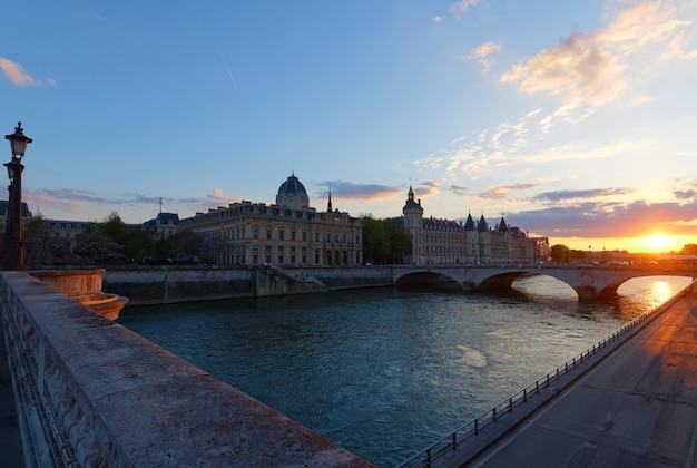 Zdjęcie dramatyczny zachód słońca nad rzeką seine i conciergerie w paryżu francja z mostem pont neuf kolorowe tło podróży