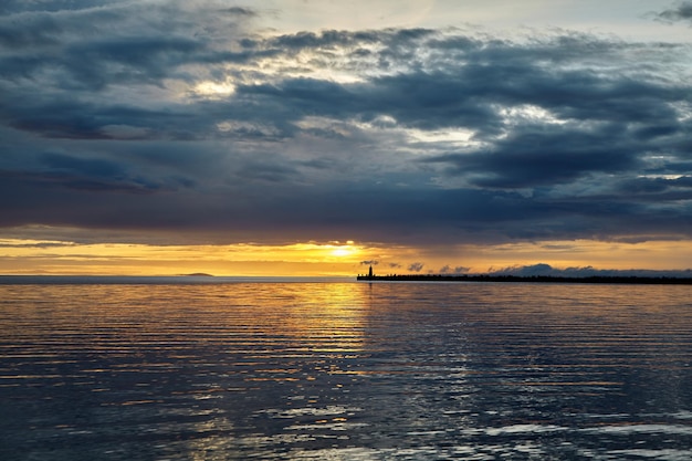 Dramatyczny zachód słońca z burzowymi chmurami przed burzą Molo morskie z latarnią morską na tle zachodzącego słońca