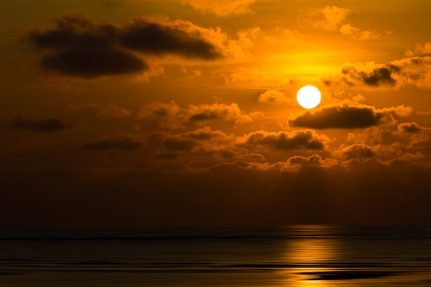 Dramatyczny zachód słońca za chmurami nad morzem