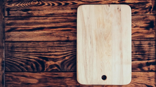 Drewniana deska do krojenia na brązowym tle stołu