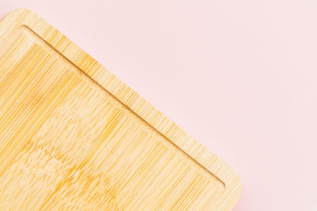 Drewniana deska do krojenia na różowym tle do koncepcji przyborów kuchennych