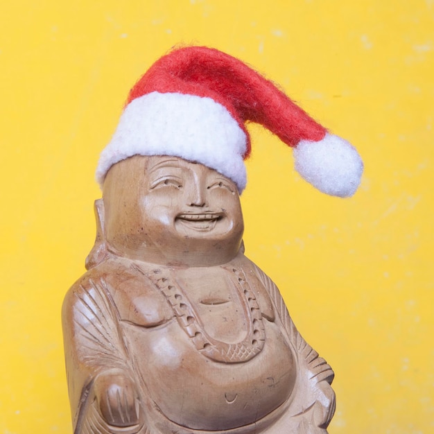 Drewniana figurka szczęśliwego Buddy w zabawkowym świątecznym kapeluszu