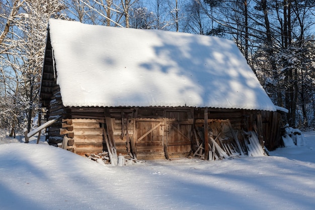 Drewniana konstrukcja w lesie. Używany jako stodoła na wsi. Zdjęcie jest robione z bliska przy słonecznej pogodzie w sezonie zimowym. Na powierzchni jest śnieg