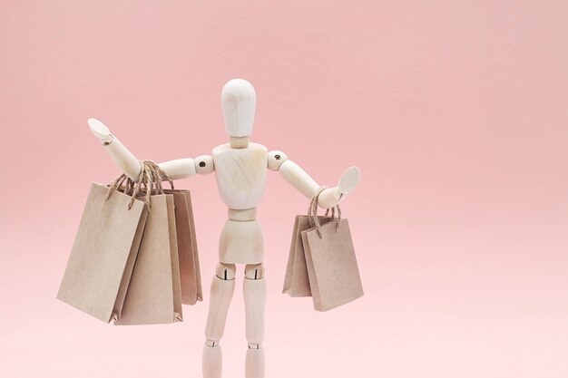 Drewniana lalka z rzemieślniczymi papierowymi torbami na zakupy sprzedaż lub koncepcja zakupów