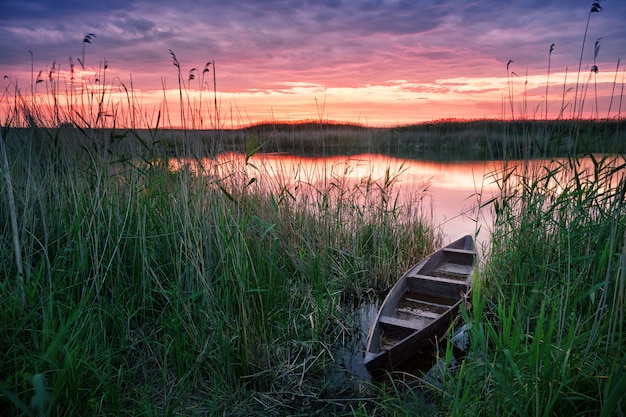 Drewniana łódź na jeziorze przy zmierzchem