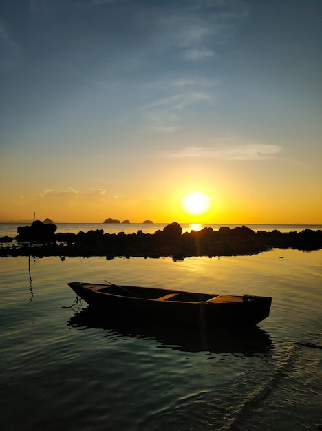 Drewniana łódź zacumowana w płytkiej wodzie w pobliżu plaży o zachodzie słońca Romantyczny krajobraz