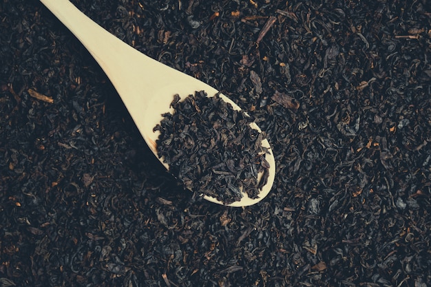 drewniana łyżka z posypaną czarną herbatą. Stonowanych