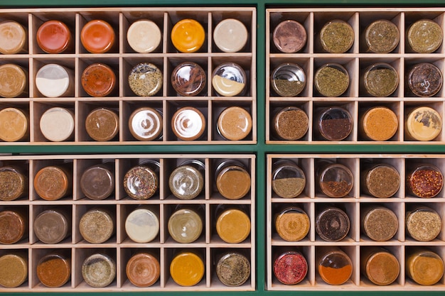 Drewniana półka z sześciennych komórek wypełnionych kolorowymi słojami z różnymi przyprawami, herbatą, ziołami, solą