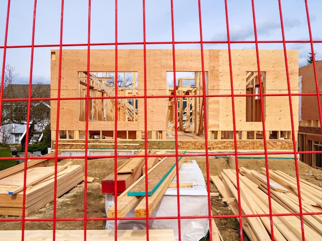 Drewniana ramka i ściany nowego domu za czerwoną siatką ogrodzenia