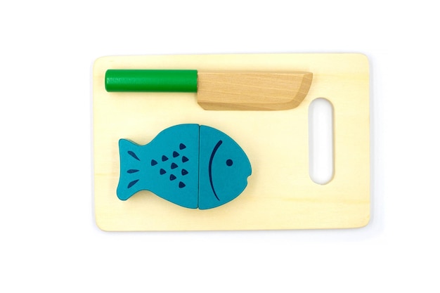 Zdjęcie drewniana ryba na magnesach leży na desce do krojenia z nożem drewniane zabawki dla dzieci