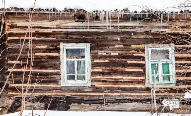 Drewniana ściana z bali z oknami starego wiejskiego domu