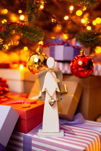 Drewniana zabawka anioła pod choinką na prezentach Koncepcja świętowania Bożego Narodzenia